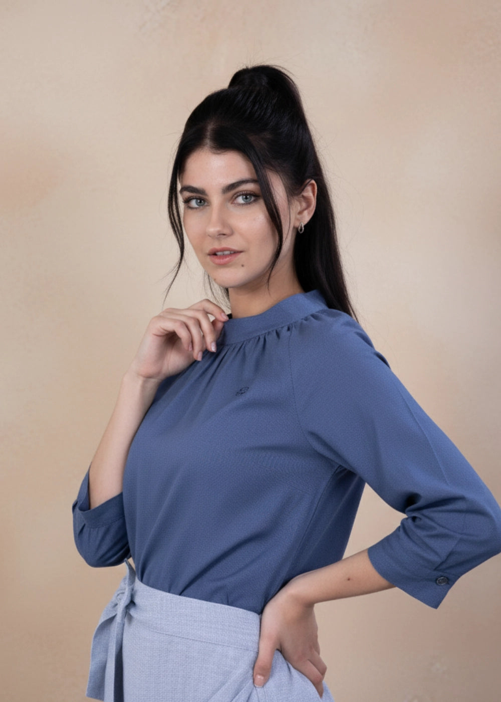Model wearing Karee’s Bio Blue 3/4 Sleeve Linen Top — high-neck linen blouse with gathered neckline, roll-up sleeves, and eco-conscious detailing, crafted in breathable blue linen.